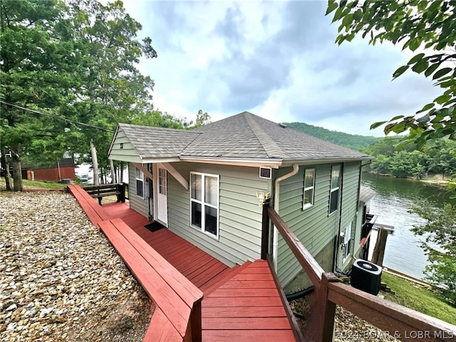 rear view of property featuring central air condition unit and a water view