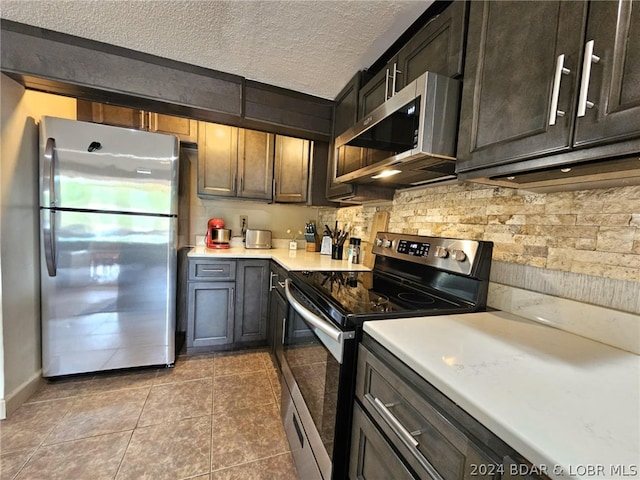 kitchen with appliances with stainless steel finishes, dark brown cabinets, tasteful backsplash, a textured ceiling, and tile patterned floors