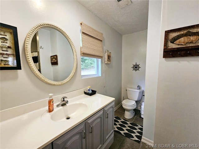 bathroom featuring vanity, tile patterned flooring, toilet, and a textured ceiling