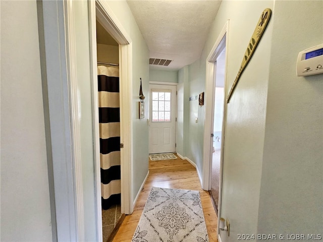 doorway to outside with light hardwood / wood-style floors and a textured ceiling