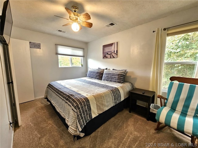 bedroom featuring dark colored carpet, a textured ceiling, and ceiling fan