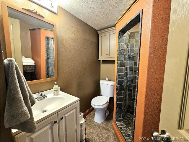 bathroom featuring vanity, toilet, a textured ceiling, and a shower