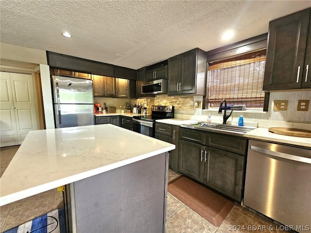 kitchen featuring dark brown cabinetry, sink, stainless steel appliances, and a kitchen island