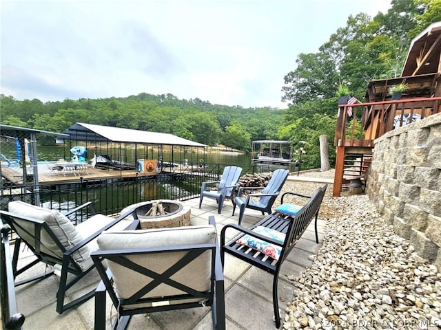 view of patio / terrace featuring a water view, a dock, and an outdoor fire pit