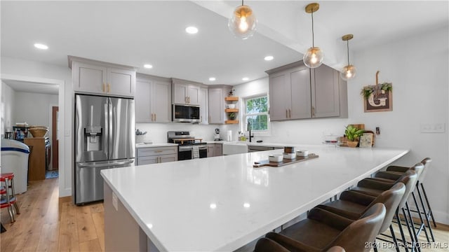 kitchen featuring appliances with stainless steel finishes, pendant lighting, a kitchen bar, and kitchen peninsula