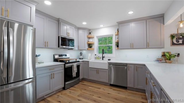 kitchen featuring stainless steel appliances, sink, light wood-type flooring, and gray cabinets