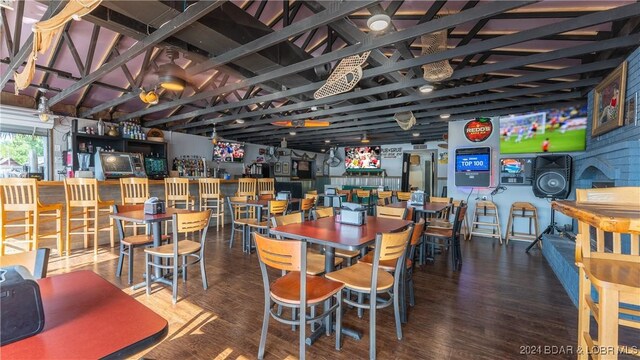 dining area with vaulted ceiling, bar, and hardwood / wood-style floors