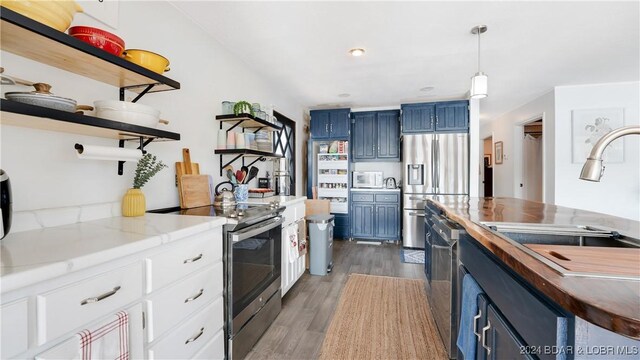 kitchen featuring butcher block countertops, stainless steel appliances, dark hardwood / wood-style floors, white cabinetry, and blue cabinets