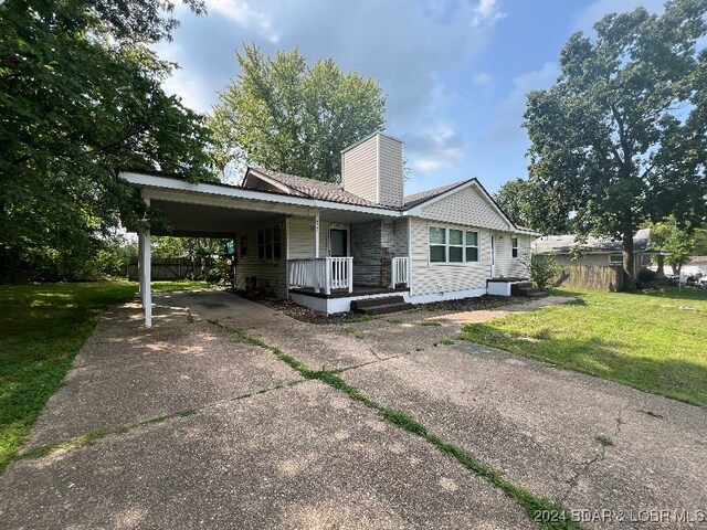 view of front of home with a porch, a carport, and a front yard