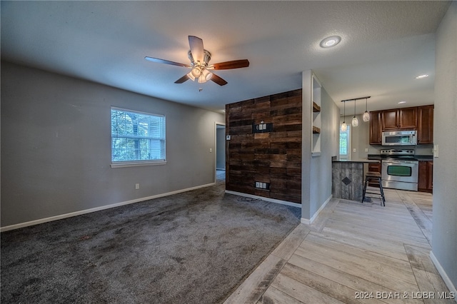 unfurnished room featuring light colored carpet, a wealth of natural light, and ceiling fan