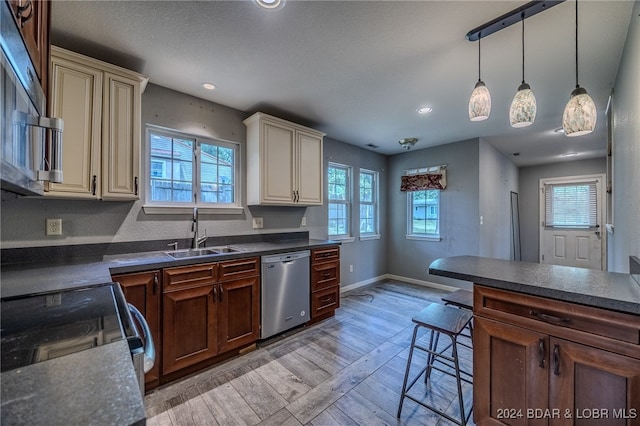 kitchen featuring light hardwood / wood-style floors, stainless steel dishwasher, cream cabinetry, and plenty of natural light