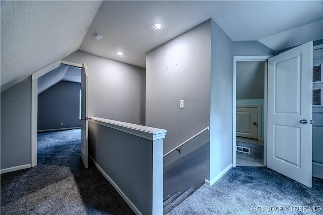 hall with carpet floors, a textured ceiling, and vaulted ceiling