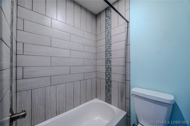 bathroom featuring tiled shower / bath combo and toilet