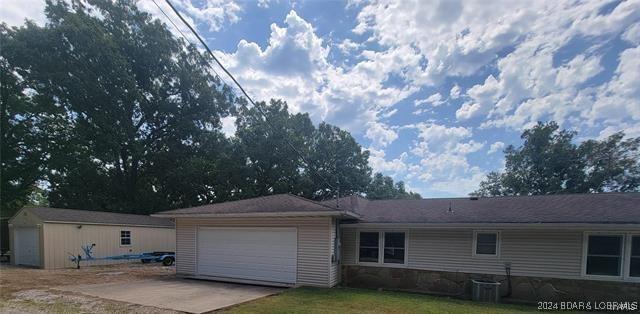 back of property with a garage, driveway, and central air condition unit