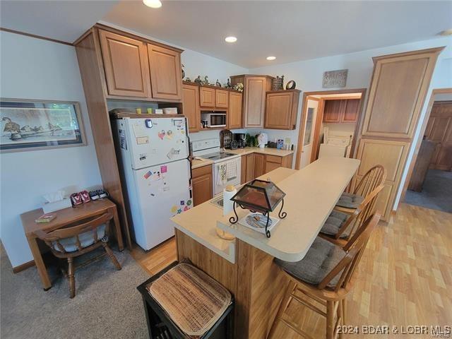 kitchen with white appliances, light countertops, a kitchen island, and a kitchen breakfast bar