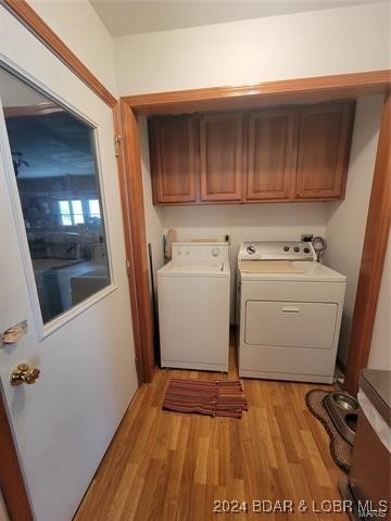 laundry area featuring cabinets, light hardwood / wood-style flooring, and independent washer and dryer