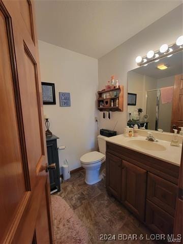 bathroom featuring toilet, a stall shower, and vanity