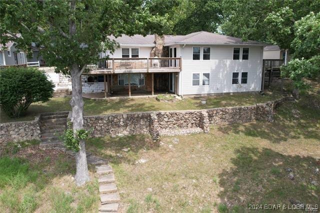 back of house featuring a lawn and a wooden deck