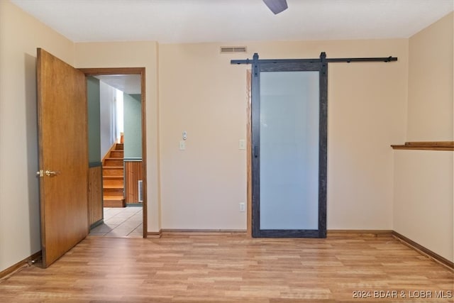 spare room featuring a barn door and light hardwood / wood-style flooring