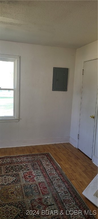 empty room featuring a textured ceiling, hardwood / wood-style floors, and electric panel