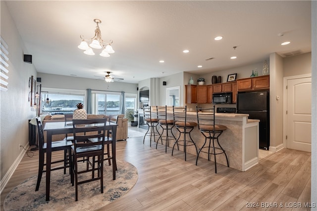 dining area with ceiling fan with notable chandelier and light wood-type flooring