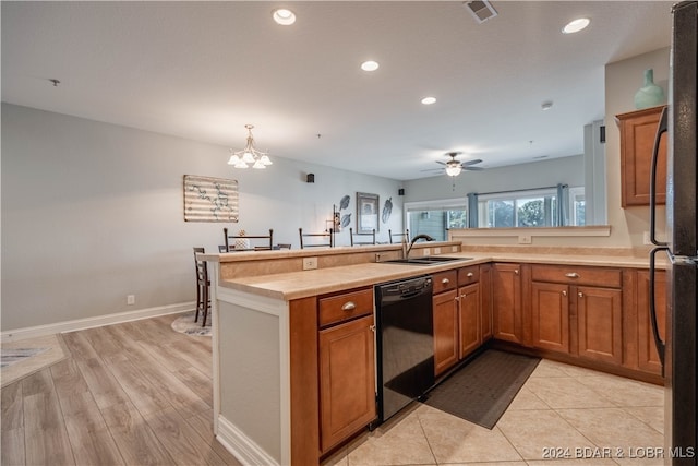 kitchen featuring ceiling fan with notable chandelier, sink, black dishwasher, light hardwood / wood-style flooring, and kitchen peninsula