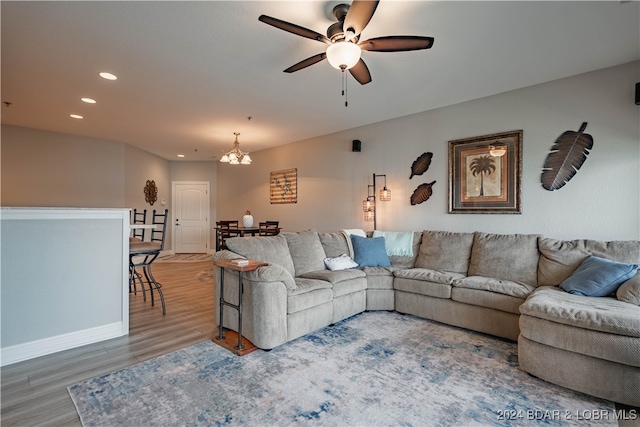 living room featuring ceiling fan with notable chandelier and hardwood / wood-style floors