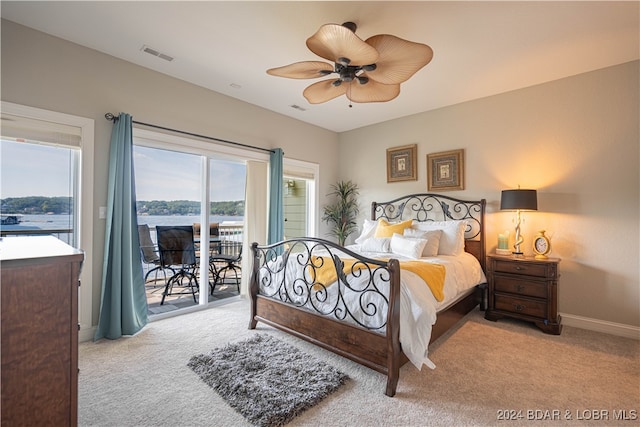 carpeted bedroom featuring access to exterior, a water view, and ceiling fan