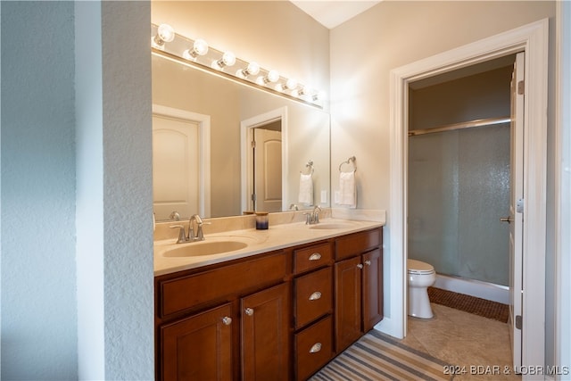 bathroom with tile patterned floors, toilet, an enclosed shower, and dual bowl vanity