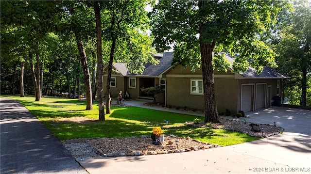 view of front of house featuring an attached garage, driveway, a front yard, and stucco siding