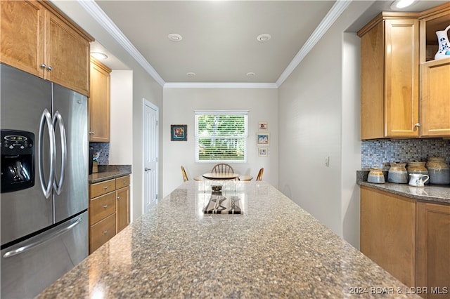 kitchen with ornamental molding, dark stone counters, stainless steel refrigerator with ice dispenser, and backsplash