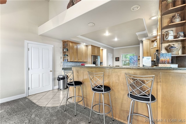 kitchen featuring stainless steel fridge, light tile patterned flooring, a breakfast bar area, and kitchen peninsula