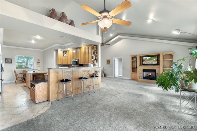 kitchen featuring crown molding, ceiling fan, stainless steel appliances, light colored carpet, and a kitchen bar