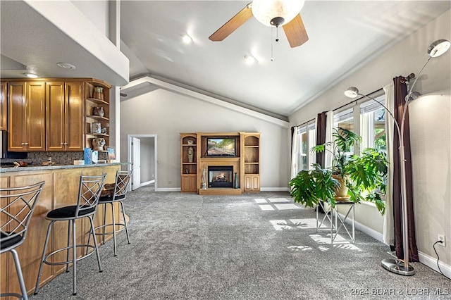 interior space featuring ceiling fan, tasteful backsplash, vaulted ceiling, and light colored carpet