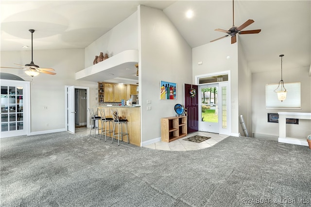 unfurnished living room with ceiling fan, light carpet, and high vaulted ceiling