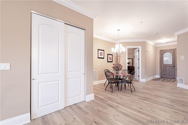 dining area with an inviting chandelier, light hardwood / wood-style floors, and ornamental molding