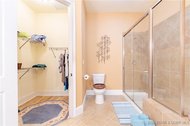 bathroom featuring tile patterned floors, toilet, and walk in shower