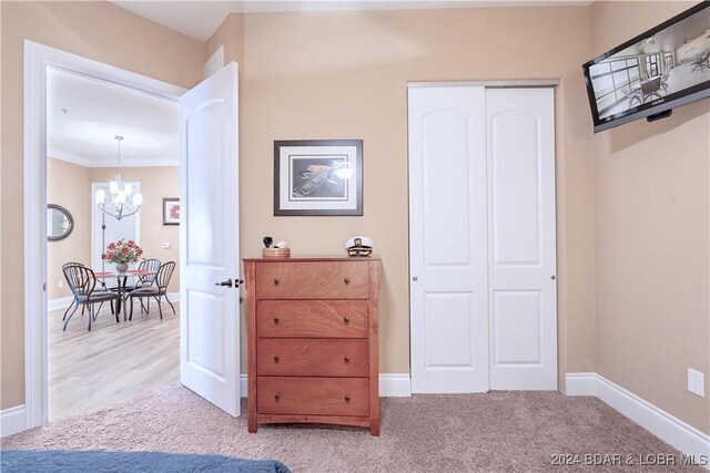 unfurnished bedroom with light colored carpet, a closet, a chandelier, and ornamental molding