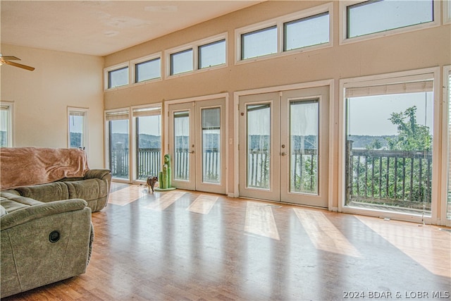 interior space with ceiling fan, a healthy amount of sunlight, a towering ceiling, and french doors