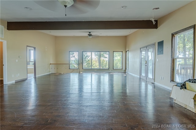 unfurnished living room with beam ceiling, dark hardwood / wood-style flooring, a wealth of natural light, and ceiling fan