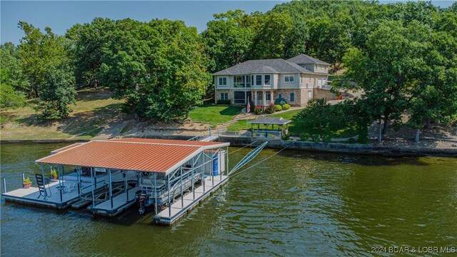 view of dock with a lawn and a water view