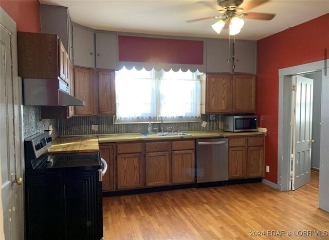 kitchen featuring light hardwood / wood-style floors, stainless steel appliances, wall chimney exhaust hood, and decorative backsplash