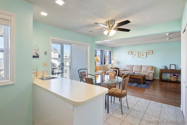 kitchen featuring a textured ceiling, ceiling fan, kitchen peninsula, light tile patterned flooring, and sink