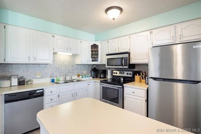 kitchen featuring stainless steel appliances, a textured ceiling, decorative backsplash, sink, and white cabinetry