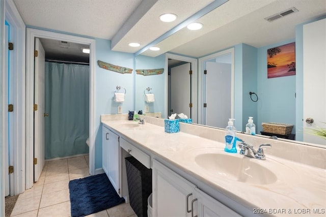 bathroom with dual vanity, a textured ceiling, and tile patterned flooring