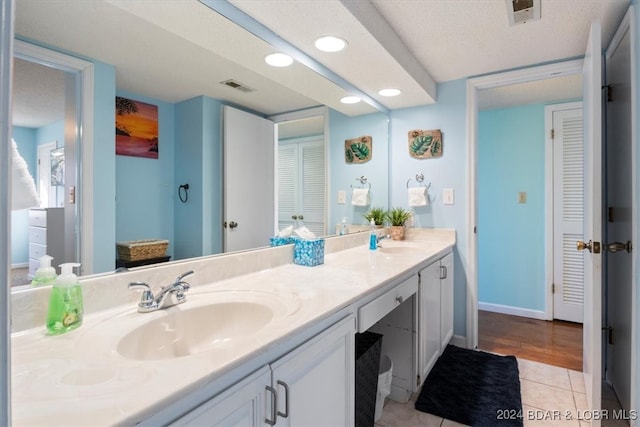 bathroom featuring a textured ceiling, tile patterned floors, and dual vanity