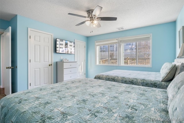 bedroom with ceiling fan and a textured ceiling