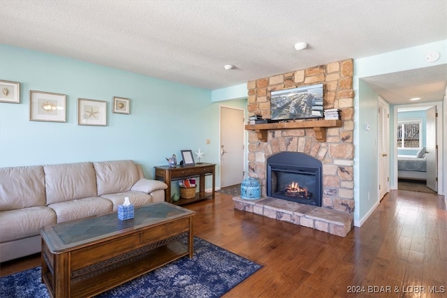 living room with a fireplace, a textured ceiling, and dark hardwood / wood-style floors