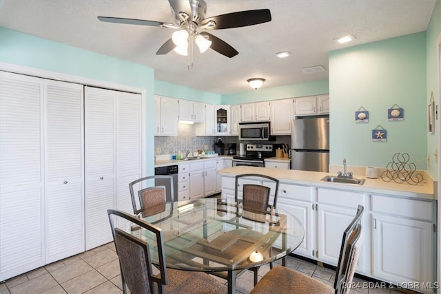 kitchen with tasteful backsplash, appliances with stainless steel finishes, white cabinets, ceiling fan, and sink