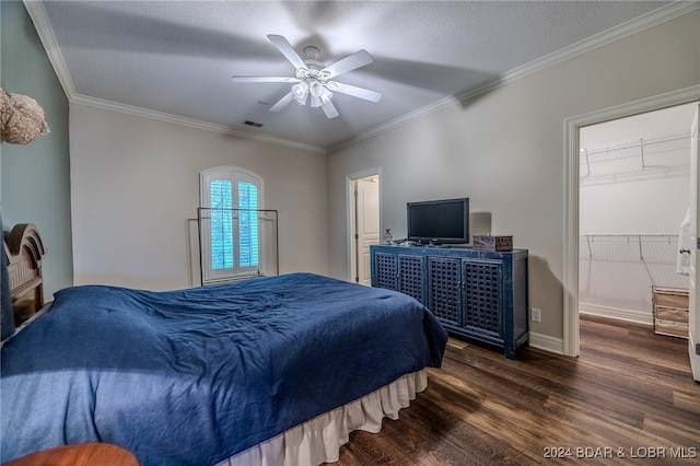 bedroom featuring dark hardwood / wood-style flooring, crown molding, a spacious closet, a closet, and ceiling fan